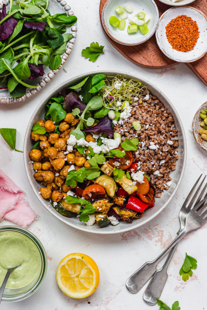 A bowl of Roasted Vegetables and Chickpeas with buckwheat and salad leaves
