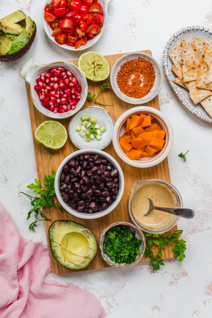 Ingredients in bowls to make salsa including black beans, sugar mango, pomegranate and avocado