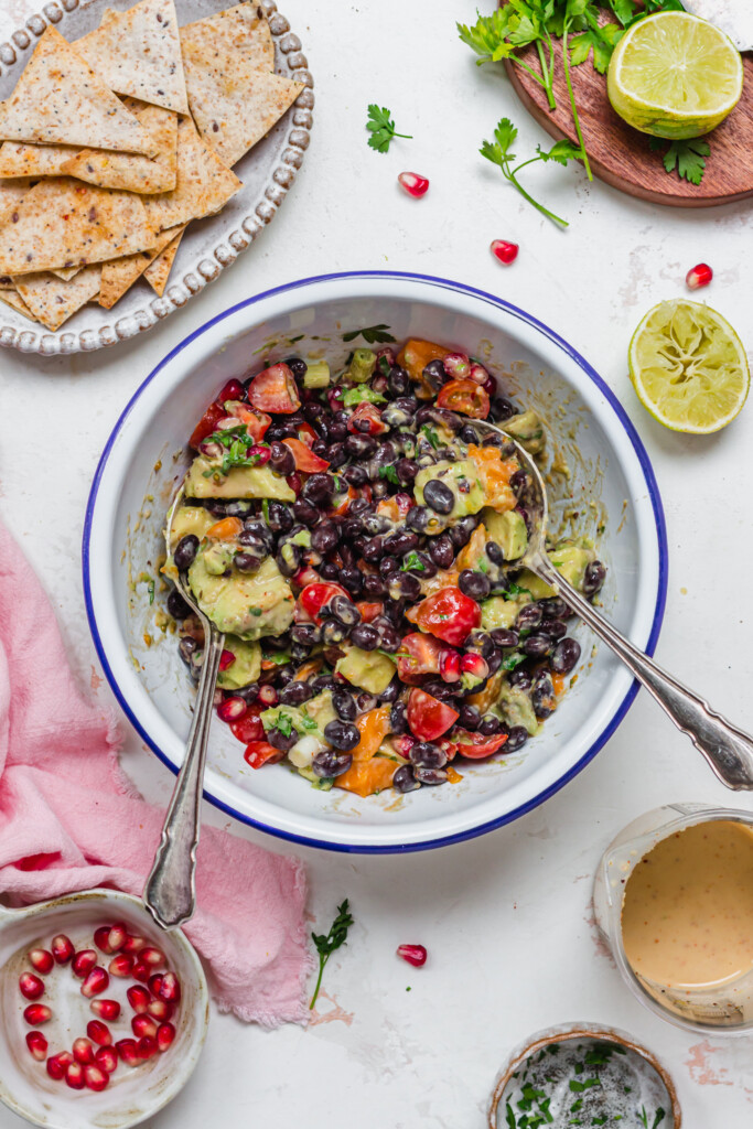 A bowl of creamy mango black bean salsa with two spoons