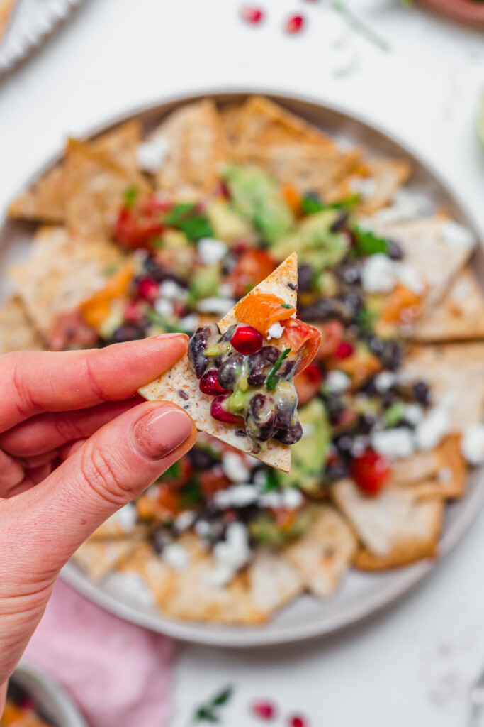 Close up of a hand holding a tortilla chip topped with black bean salsa