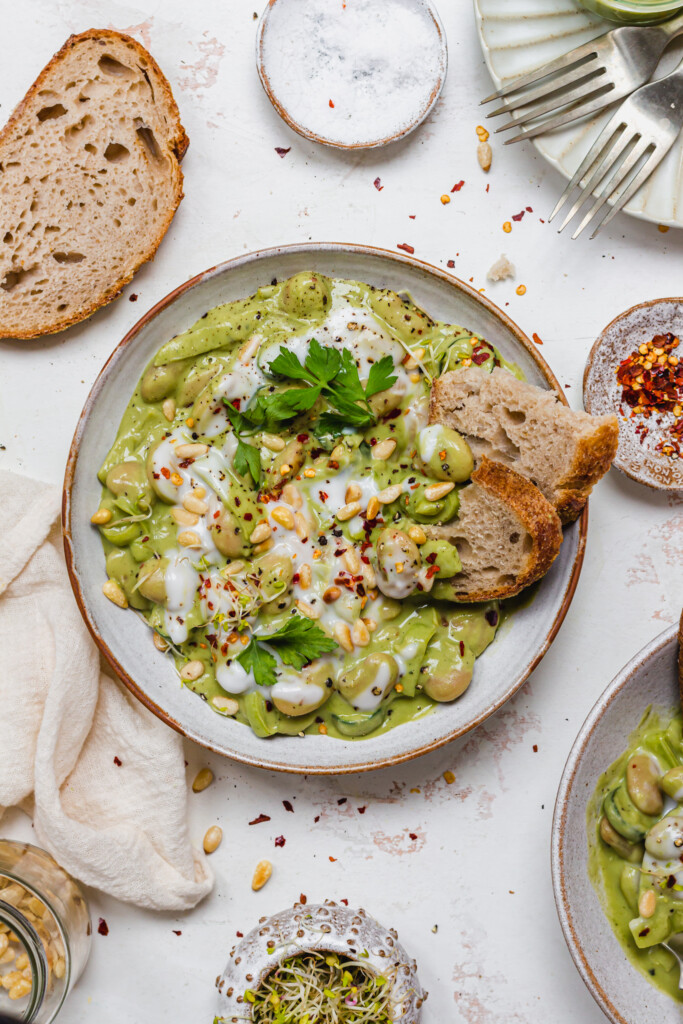 A bowl of Creamy Pesto Butterbeans with two pieces of bread inside