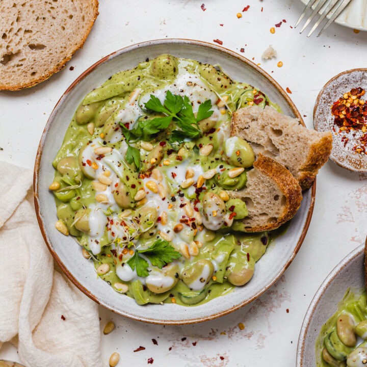 A bowl of Creamy Pesto Butterbeans with two pieces of bread inside