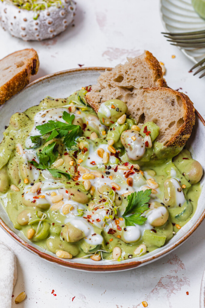 Close up of a bowl of Creamy Pesto Butterbeans with bread