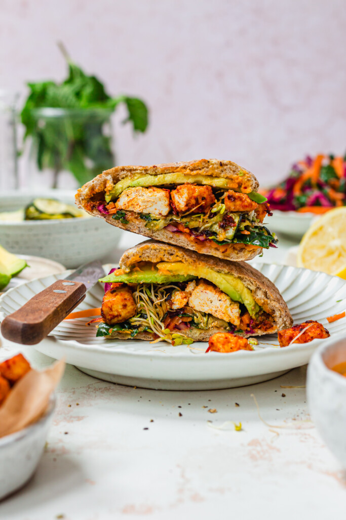 A pitta bread stacked up half on top of the other filled with harissa tofu, kale and greens
