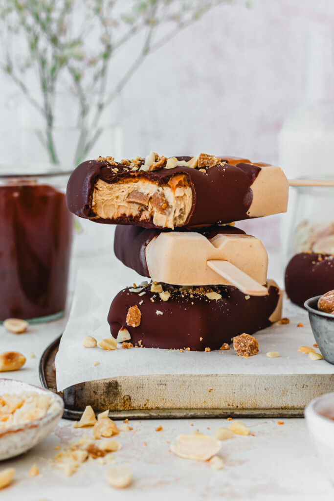 Three Peanut Butter Protein Magnum Ice Creams on top of each other with lolly sticks