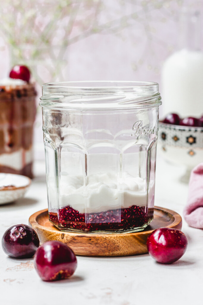 A jar with cherry jam and yoghurt inside