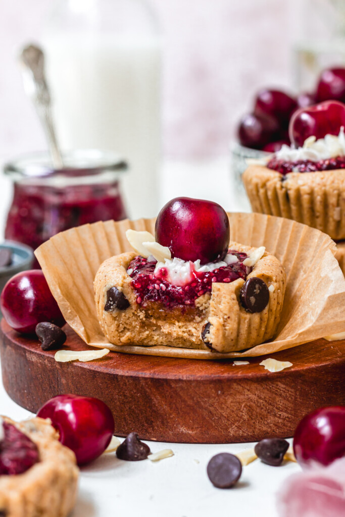A bitten Cherry Bakewell Cookie Cups with paper cases