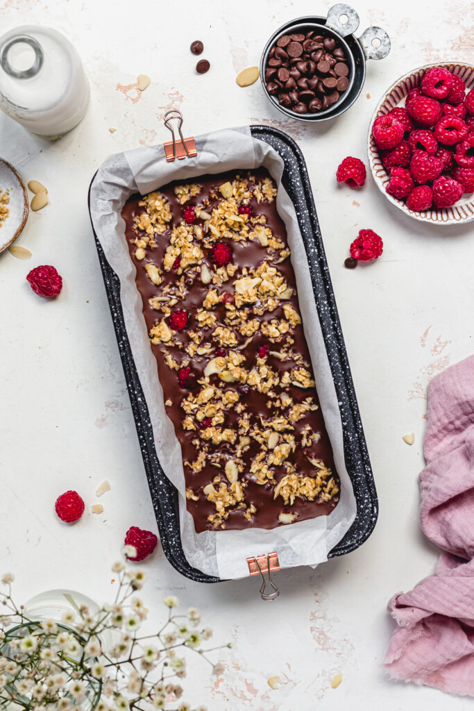 A loaf tin filled with chocolate and crumble with raspberries