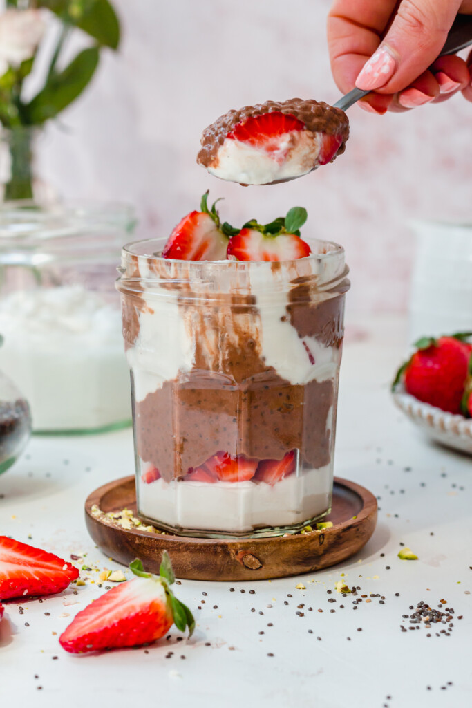 A jar of Chocolate Strawberry Chia Pudding with a spoonful