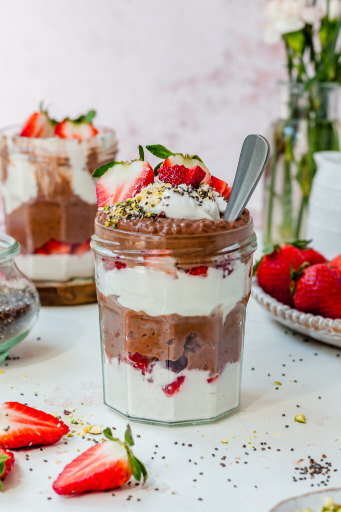 A jar of Chocolate Strawberry Chia Pudding with a spoon inside