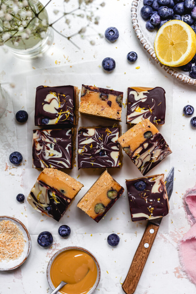 A few pieces of Lemon and Blueberry Chocolate Caramel Slices with a knife