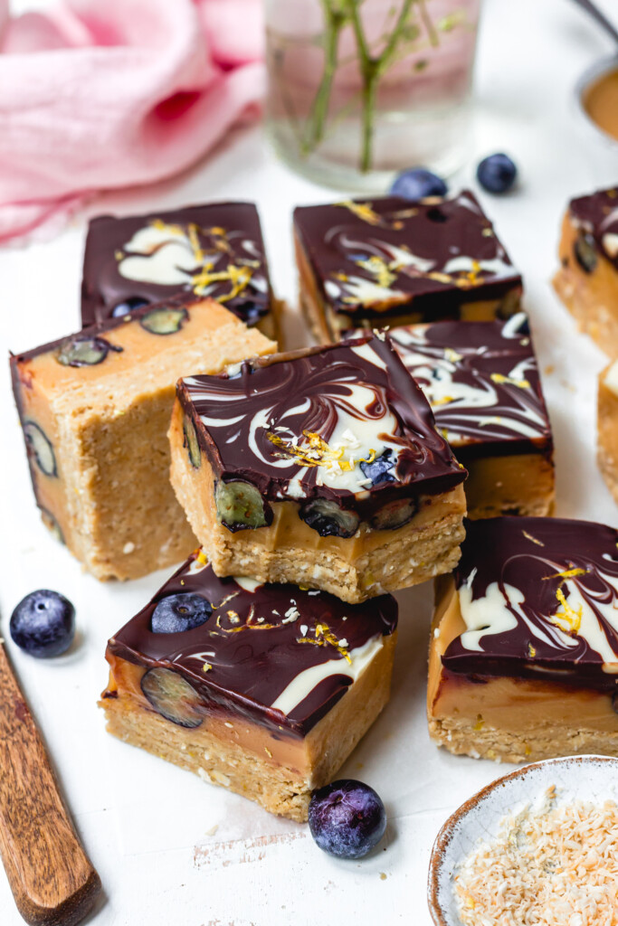 A bitten Lemon and Blueberry Chocolate Caramel Slice on top of other bars