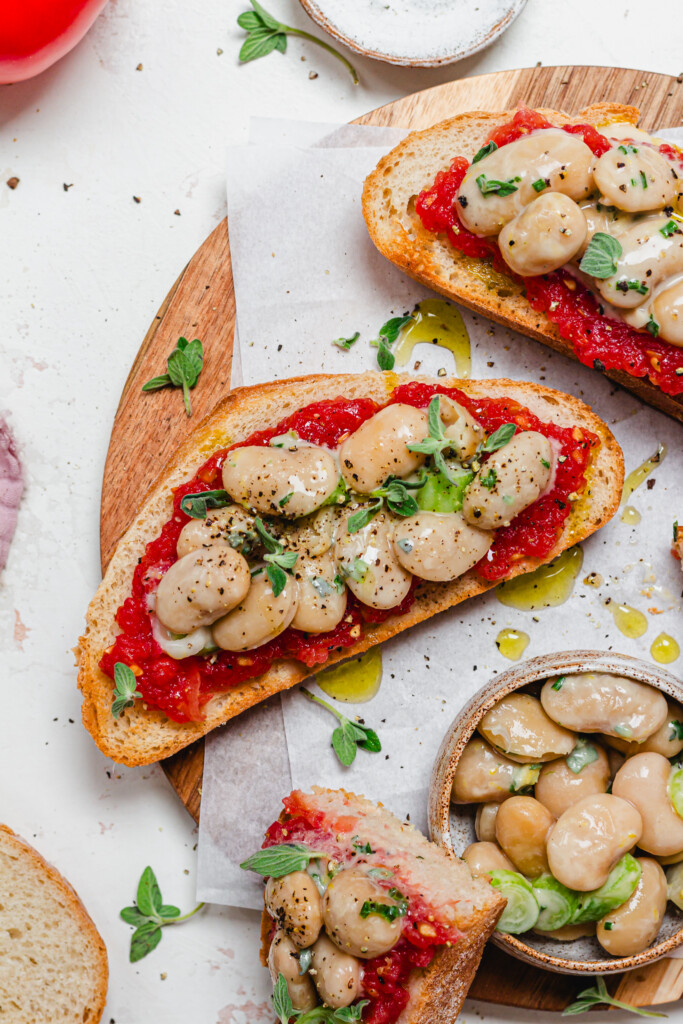 Close up of a piece of sourdough toast with tomatoes and butterbeans with herbs
