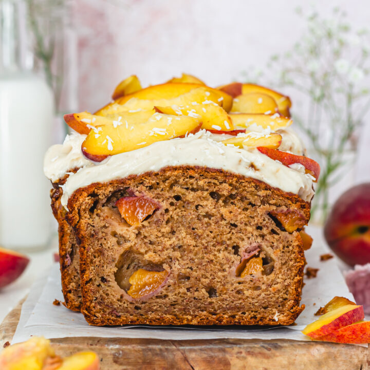 A slice leaning up against a loaf of Peaches and Cream Banana Bread