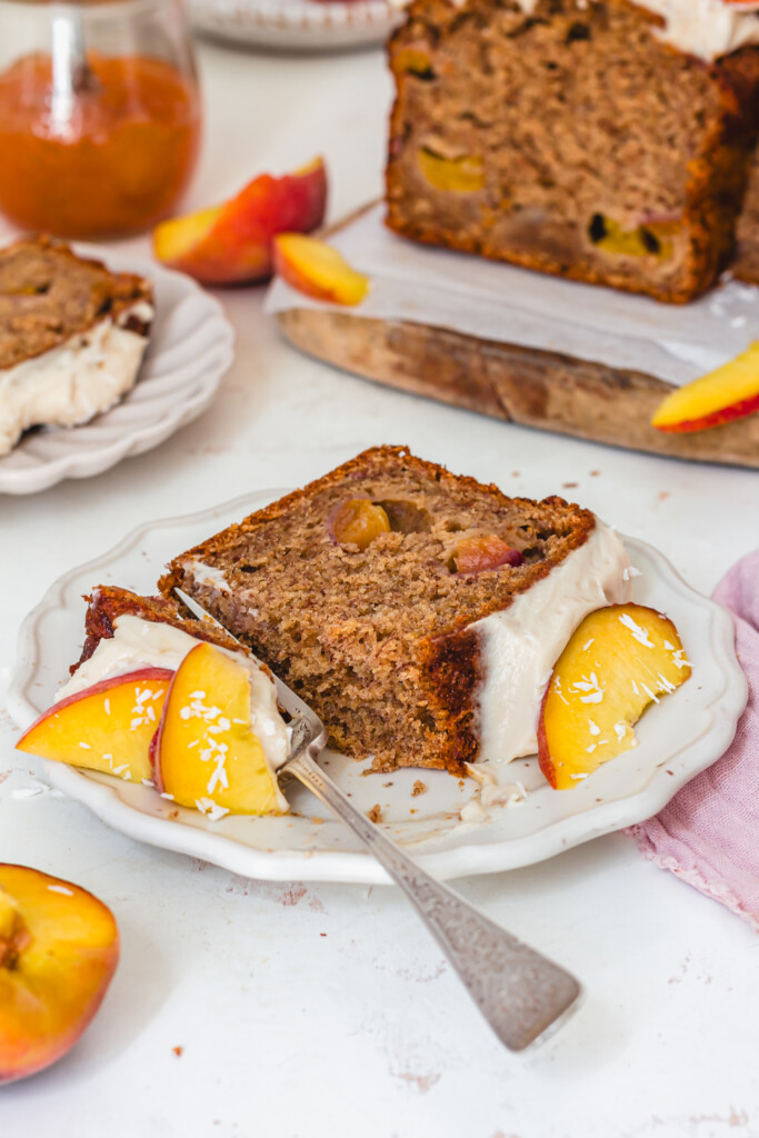 A half eaten slice of Peaches and Cream Banana Bread on a plate with a fork