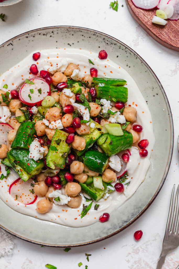 Close up of Smashed Cucumber and Chickpea Salad on some creamy yoghurt