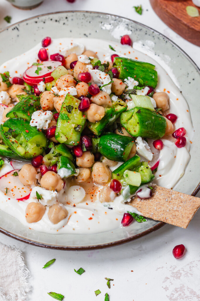 Close up of Smashed Cucumber and Chickpea Salad with a cracker