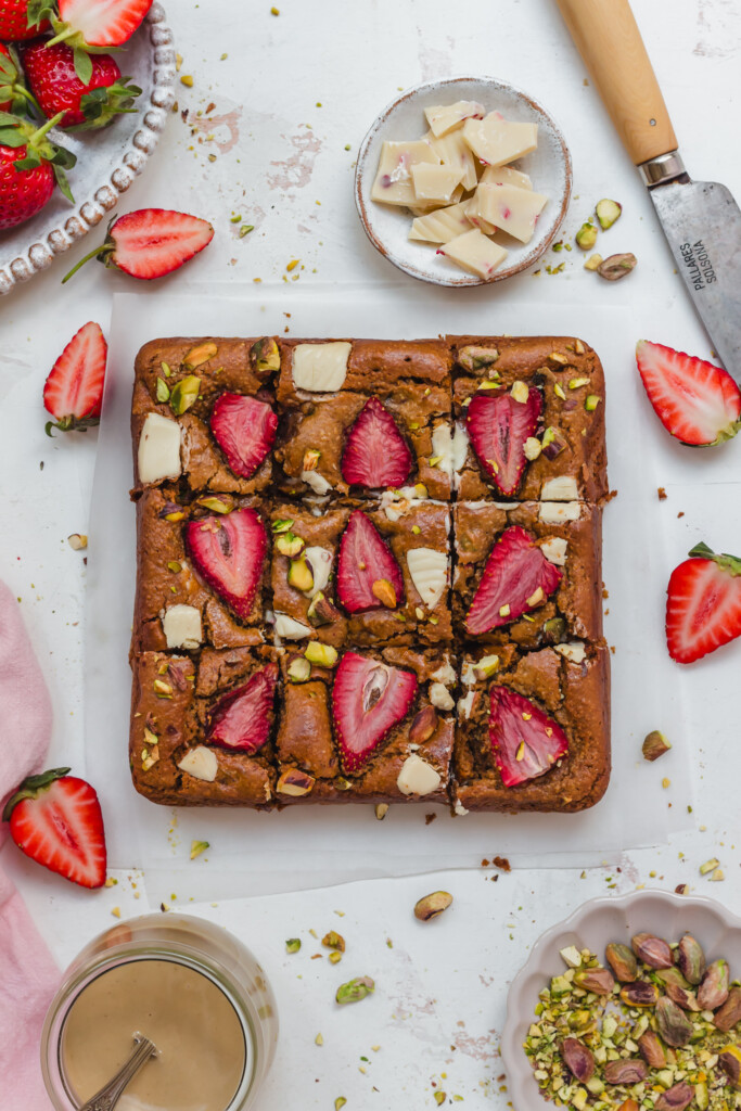 9 squares of White Chocolate Strawberry Pistachio Vegan Brownies with a knife
