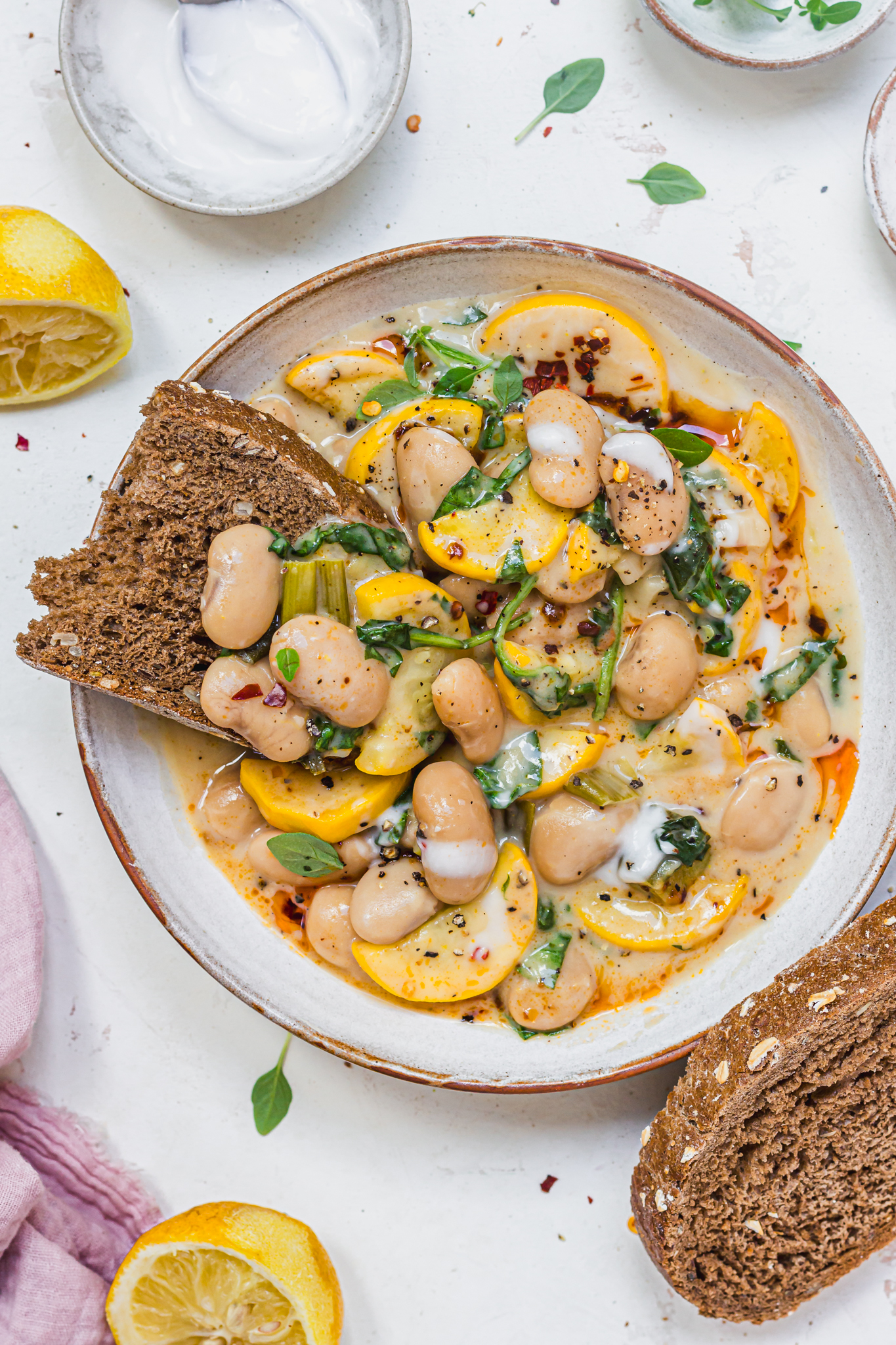 A piece of bread in a bowl of Creamy Lemony Courgette Butterbeans