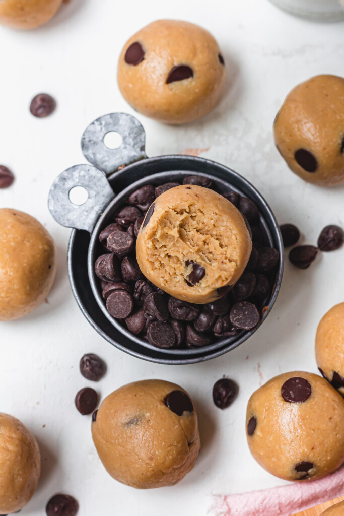 A few Healthy Chocolate Chip Cookie Dough one inside a metal cup of chocolate chips