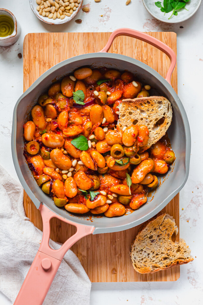 A pan of tomato and olive butterbeans with bread