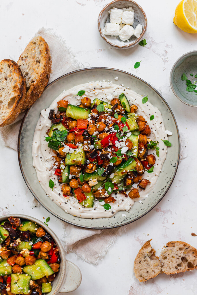 A plate of Roasted Aubergine and Chickpea Smashed Cucumbers with Whipped Tahini with bread