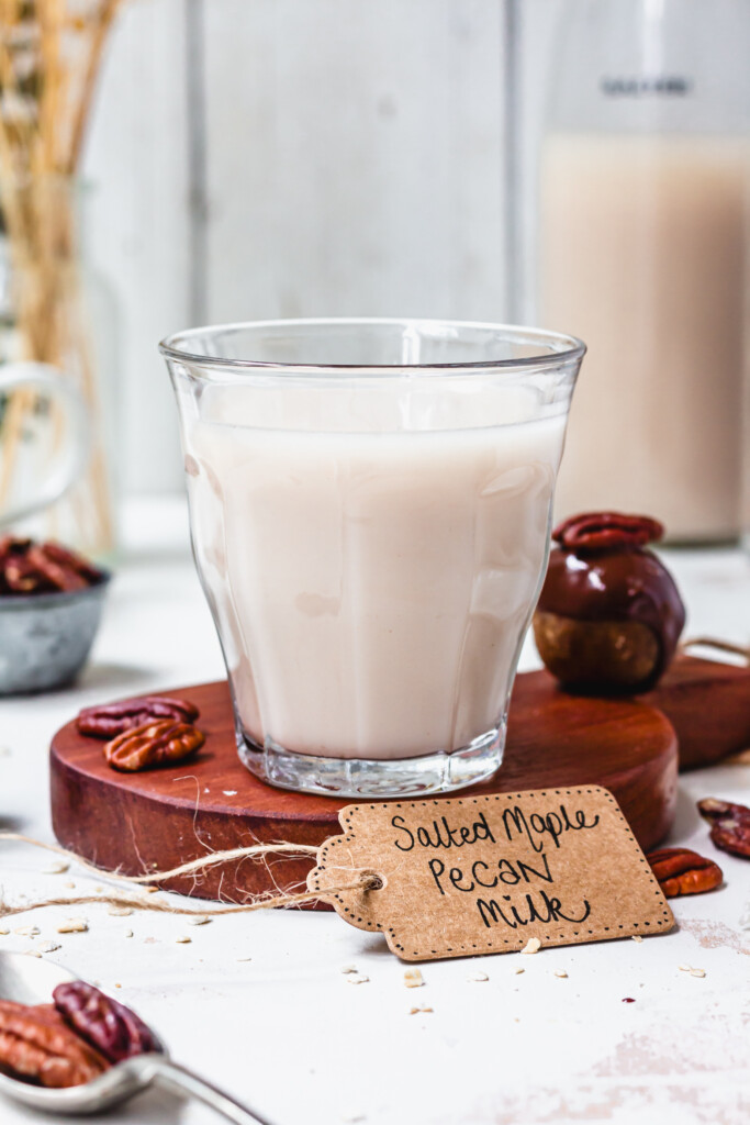 A glass of salted maple pecan milk on a wooden small tray