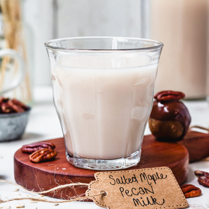 A glass of salted maple pecan milk on a wooden small tray
