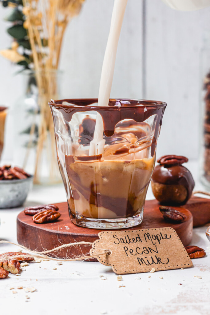 Pouring Salted Maple Pecan Milk into a glass of coffee and chocolate