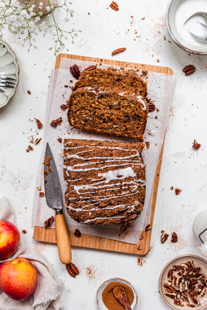 A loaf of apple and pecan cake with icing sugar drizzle