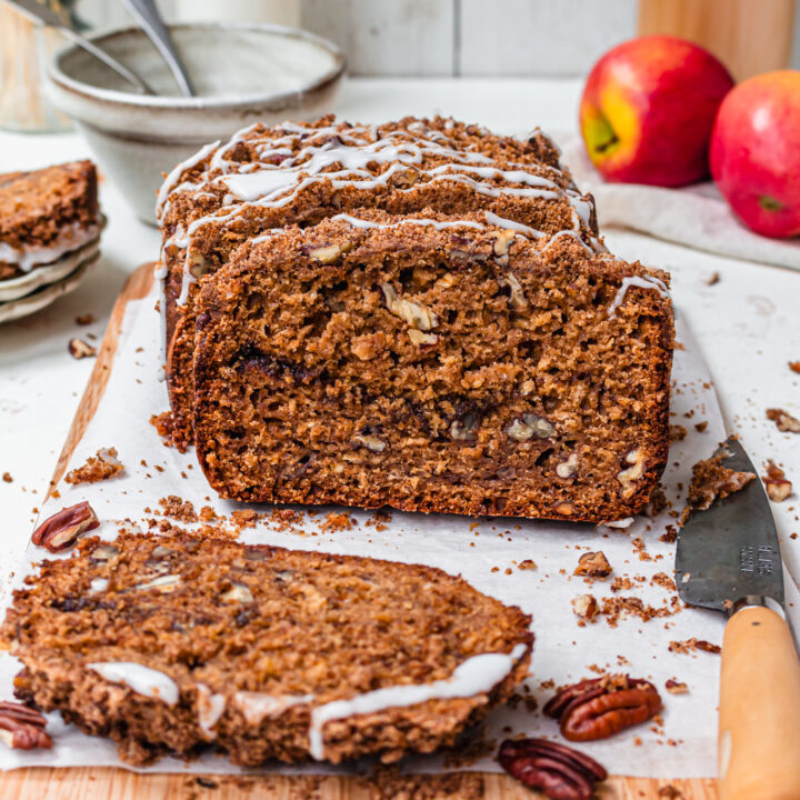 A loaf of Apple Pecan Streusel Loaf Cake with a few slices cut on a board