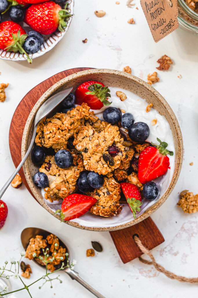 A bowl of Peanut Butter Protein Granola Clusters with berries and yoghurt