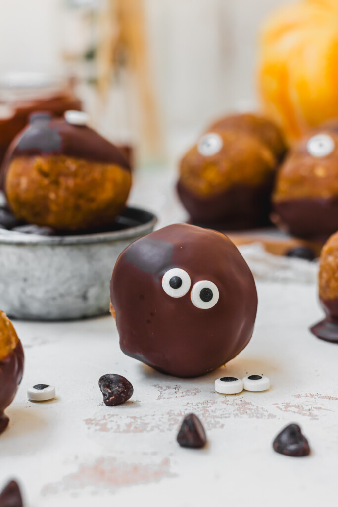A chocolate covered cake pop with two eyes