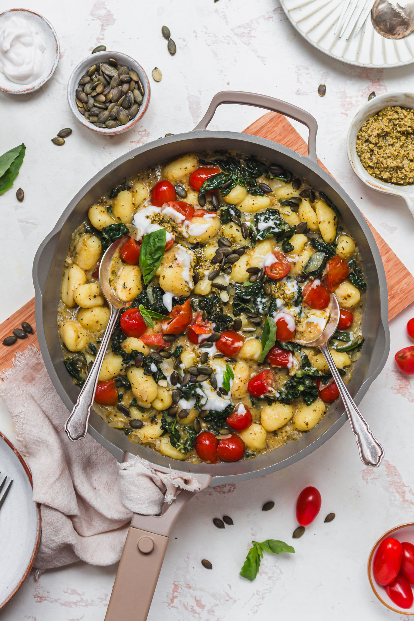 A pan of Creamy Pesto and Tomato Gnocchi with two spoons