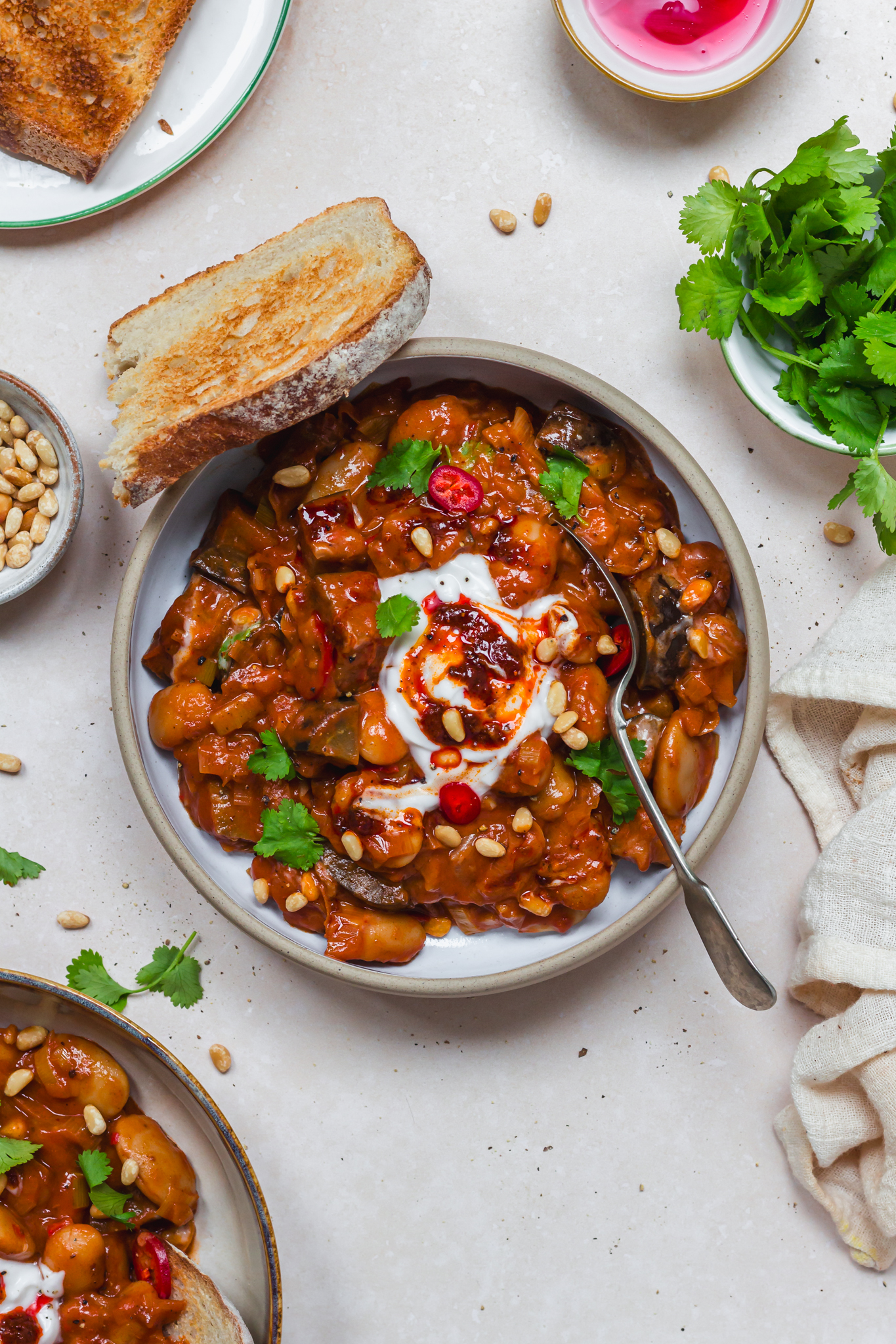 A bowl of Creamy Harissa Leek Aubergine and Butterbeans with bread