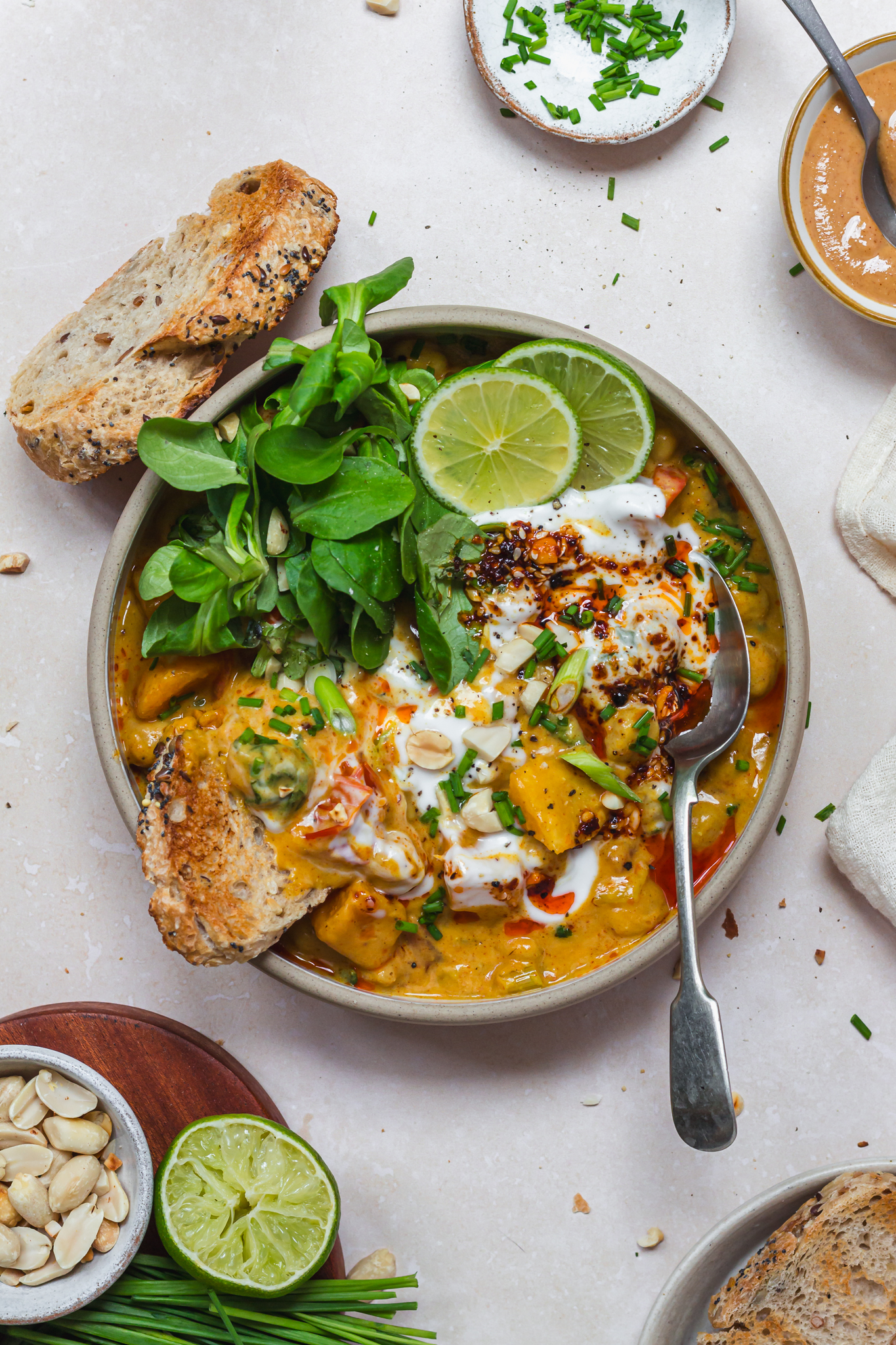 A bowl of Squash Chickpea and Peanut Butter Curry with spoon and bread