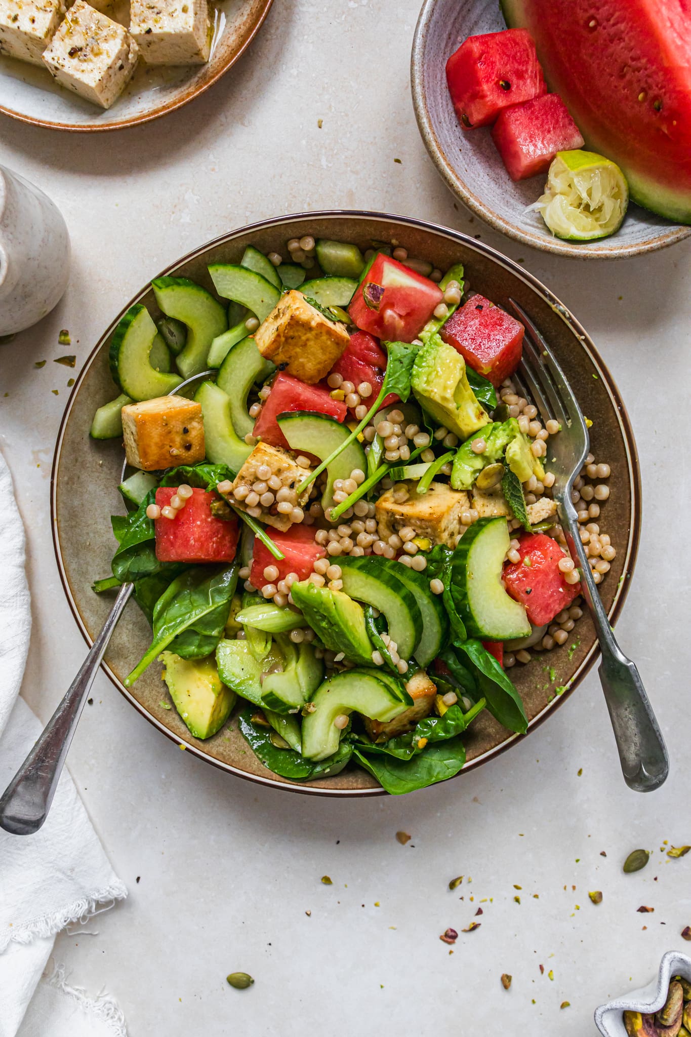 A tossed together bowl of Watermelon Hot Honey Tofu Halloumi Couscous Salad